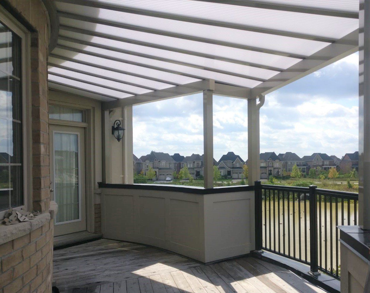 A balcony with a clear roof and a view of a lake