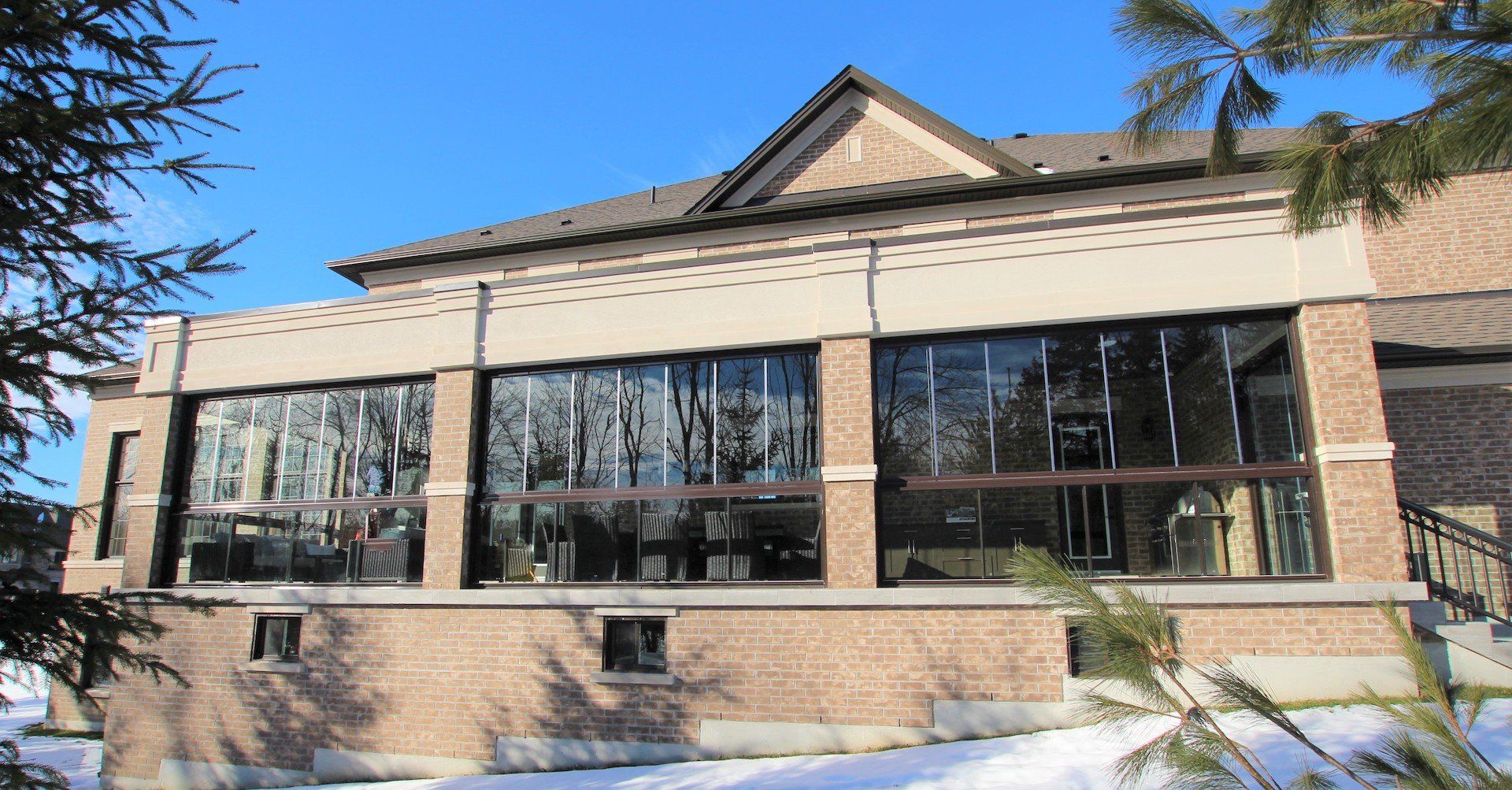A large brick building with a lot of windows is surrounded by snow and trees.