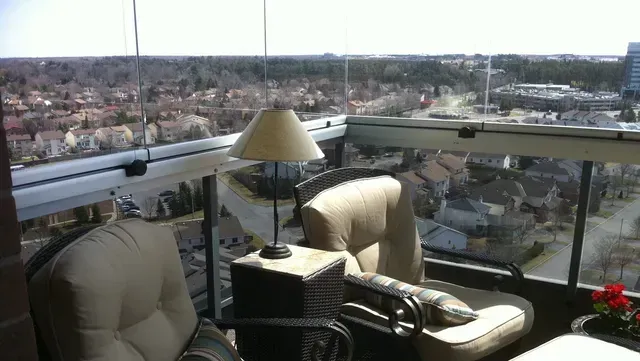 A balcony with chairs and a lamp overlooking a city