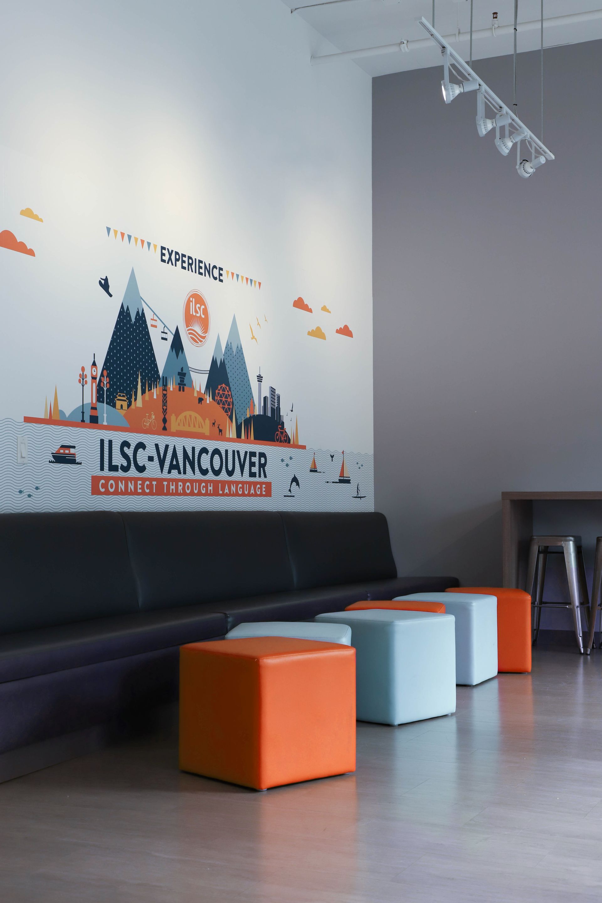 Lobby with black bench, orange and light blue ottomans, and a “San Francisco” wall mural.