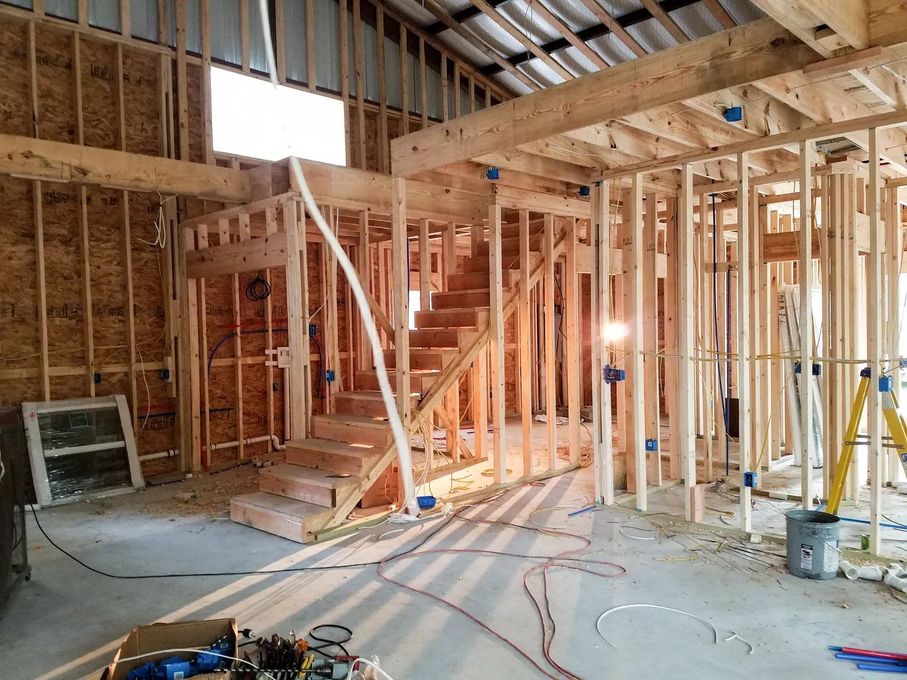 Framing of a two-story structure, including stairs, electrical wiring, and unfinished walls.