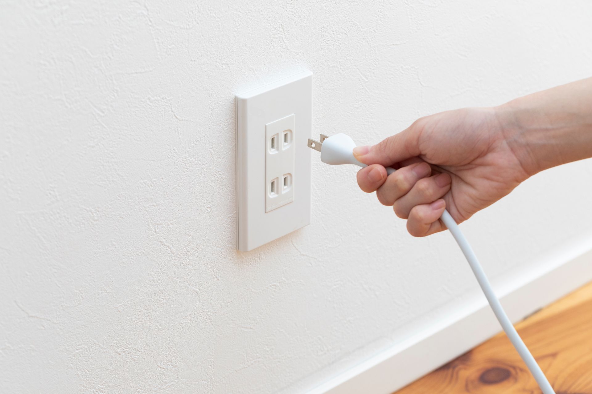 a person is plugging a cord into an electrical outlet