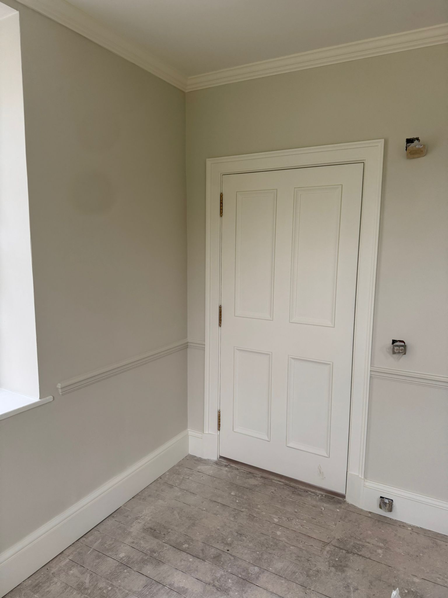 White door, trim, and light gray walls. Bare wood floor.