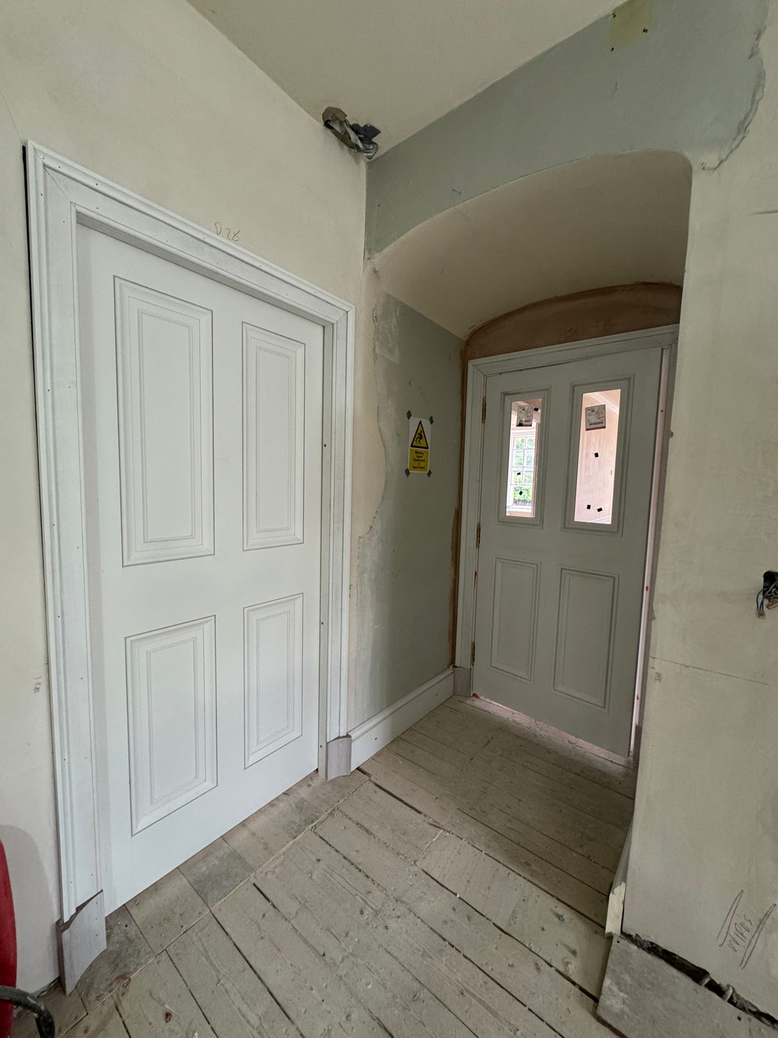 Hallway with two white doors, one with panels and the other with glass.