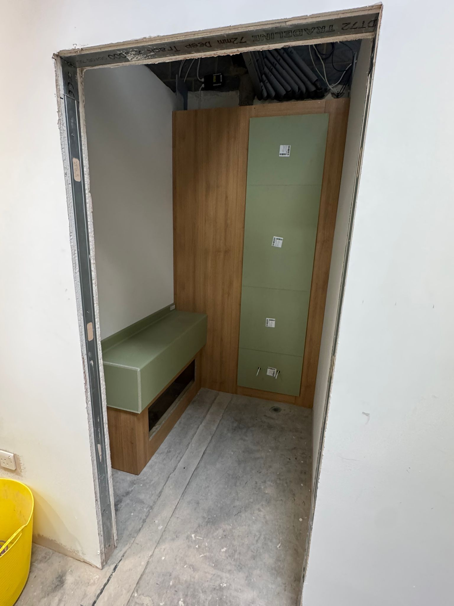 Interior space with unfinished walls, a wooden panel and green box-like furniture.