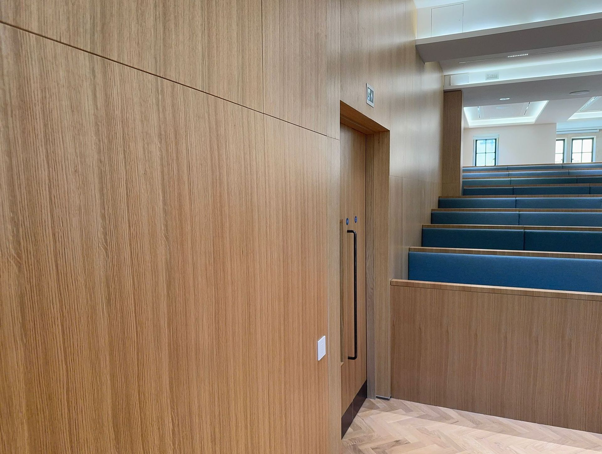 A person installing baseboard trim in a white room with a miter saw.