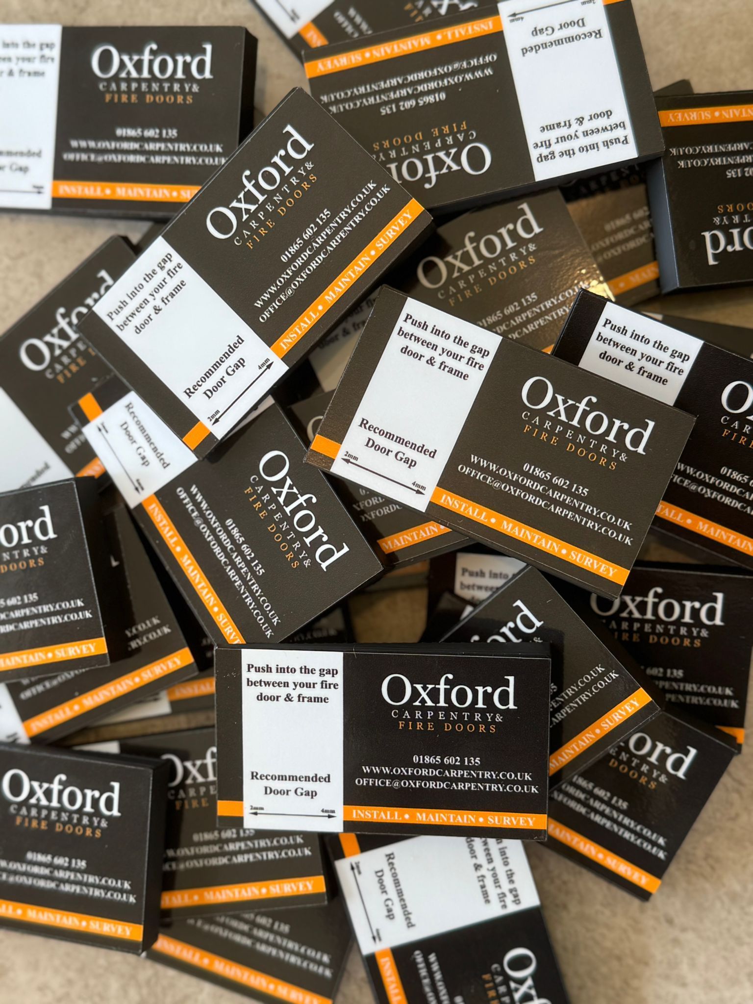 Pile of Oxford brand gap measuring tool, mostly dark with white and orange accents.