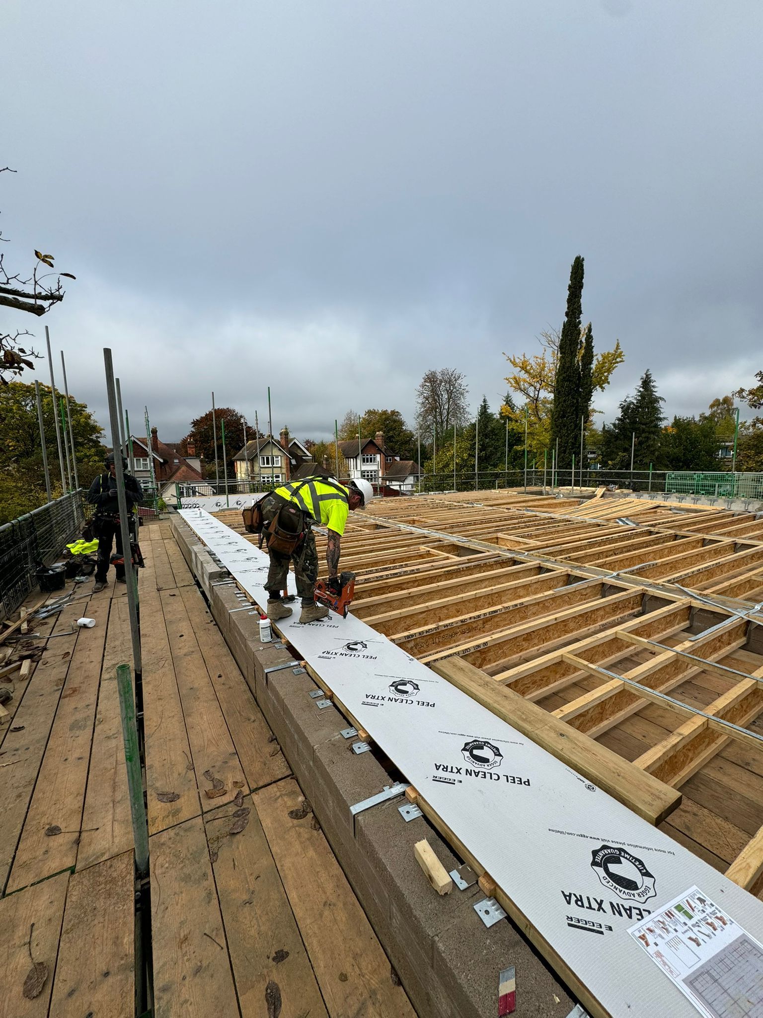 Construction workers installing roofing materials on a wooden structure.