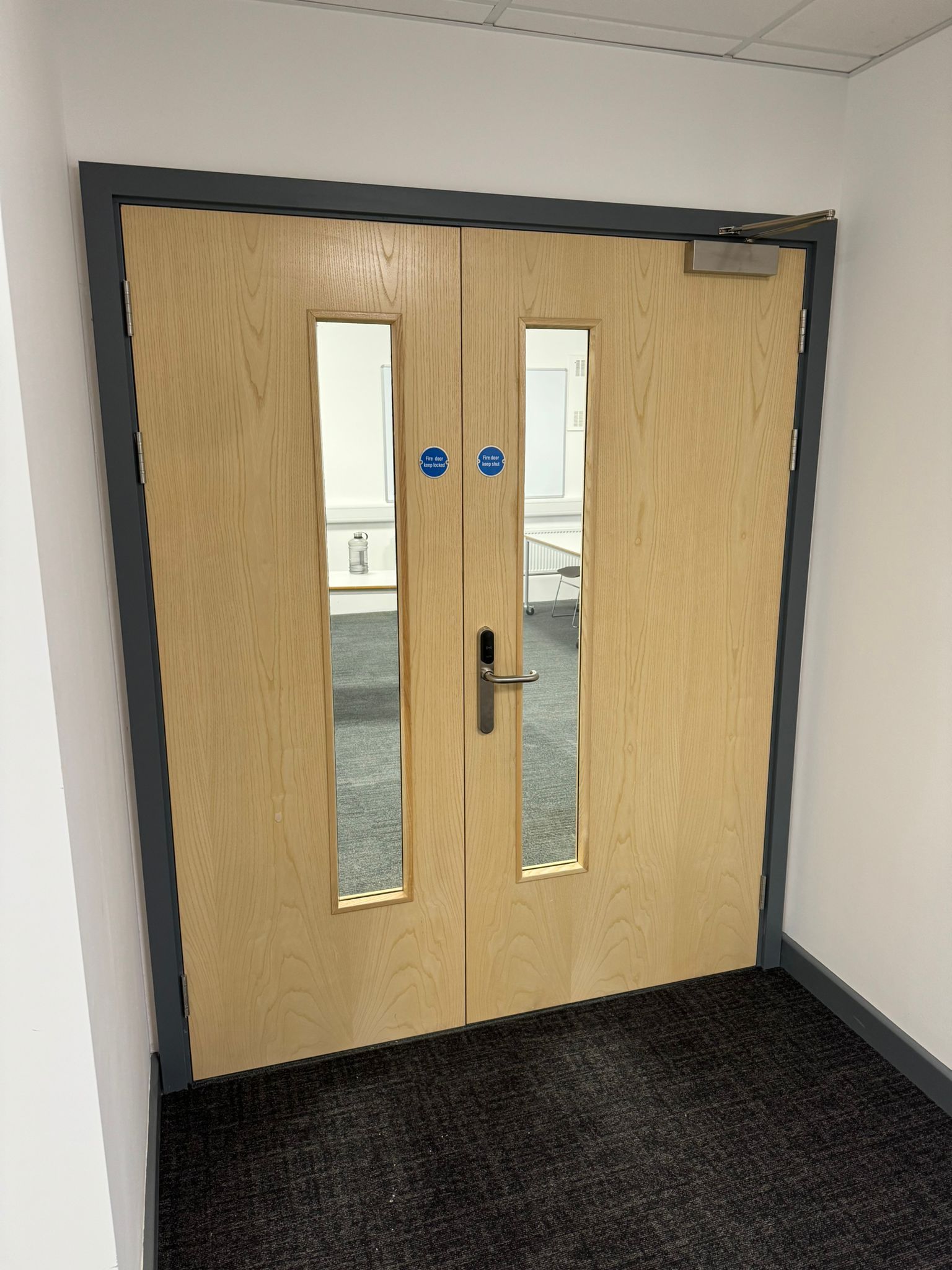 Wooden fire door with silver handle and blue safety signs.
