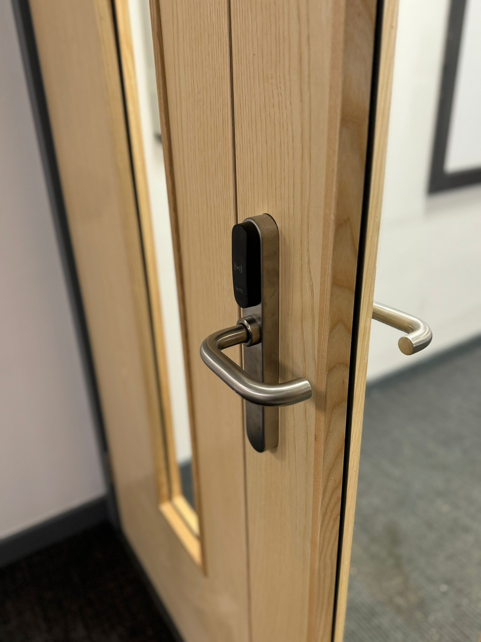 Fire door with a silver handle and a black electronic lock, with a window.
