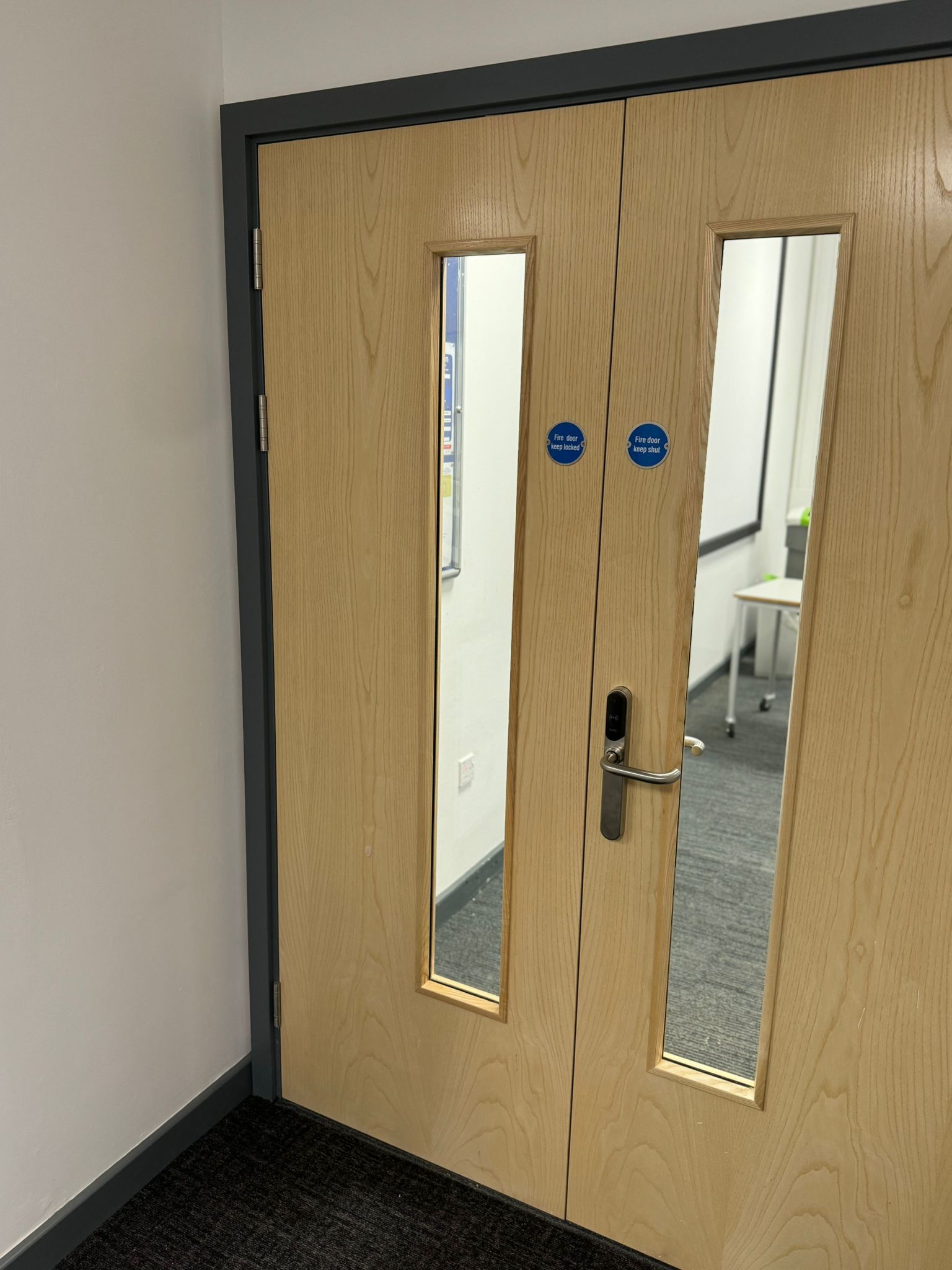 Wooden fire door with silver handle and blue safety signs.