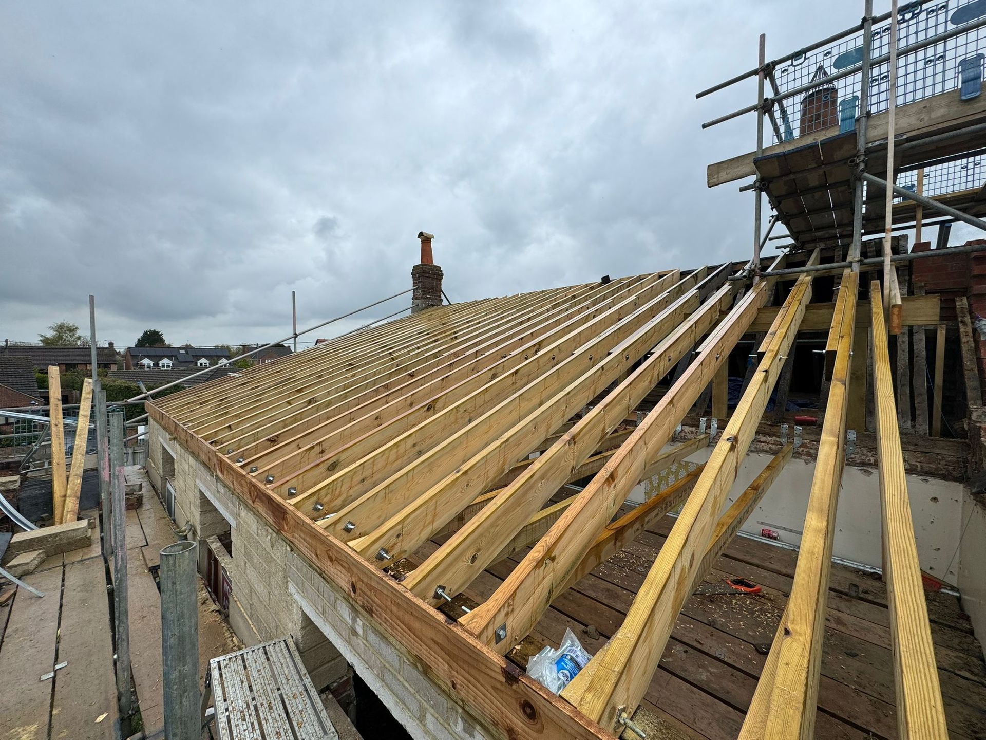 Wooden roof framing construction with a partially built dormer on a brick building.