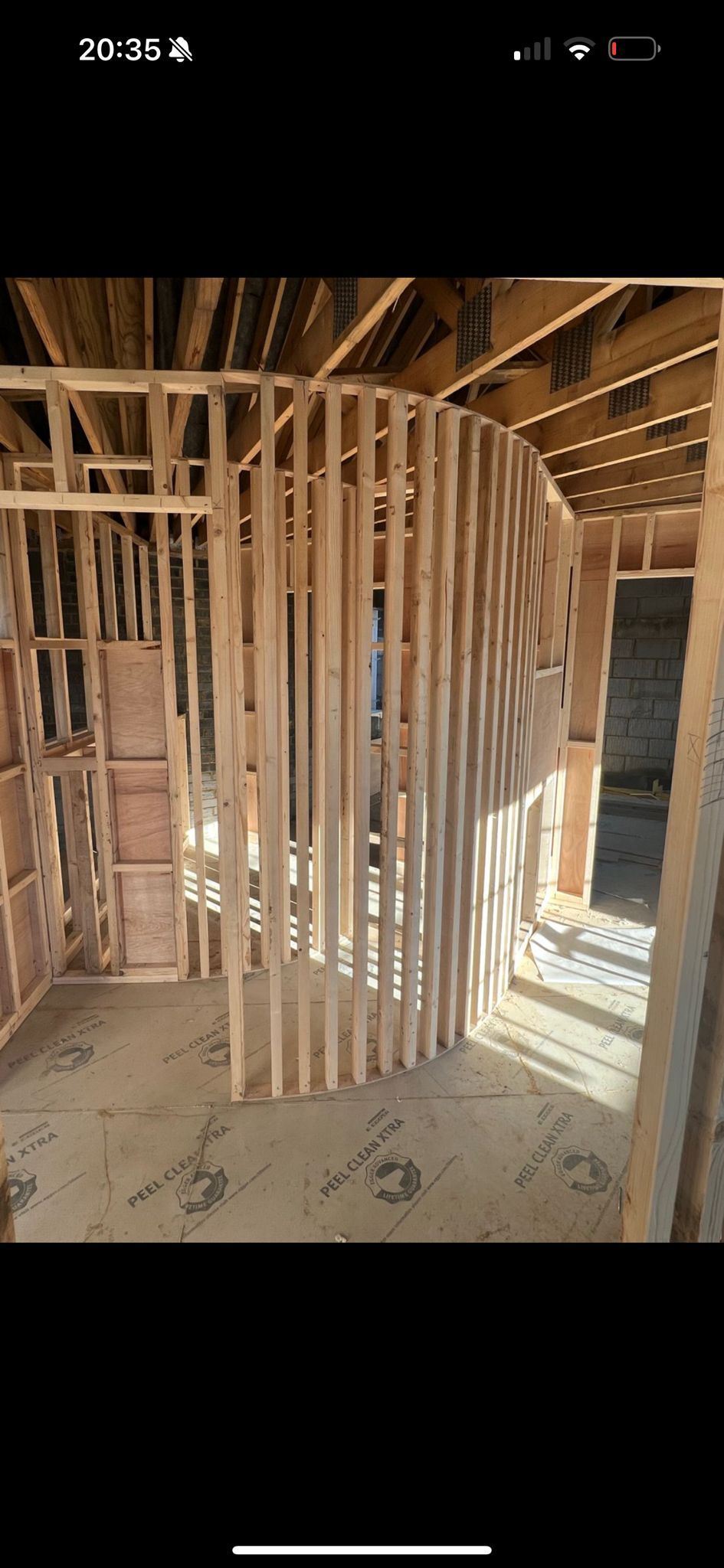 A person using a level on a wooden frame inside a building under construction.