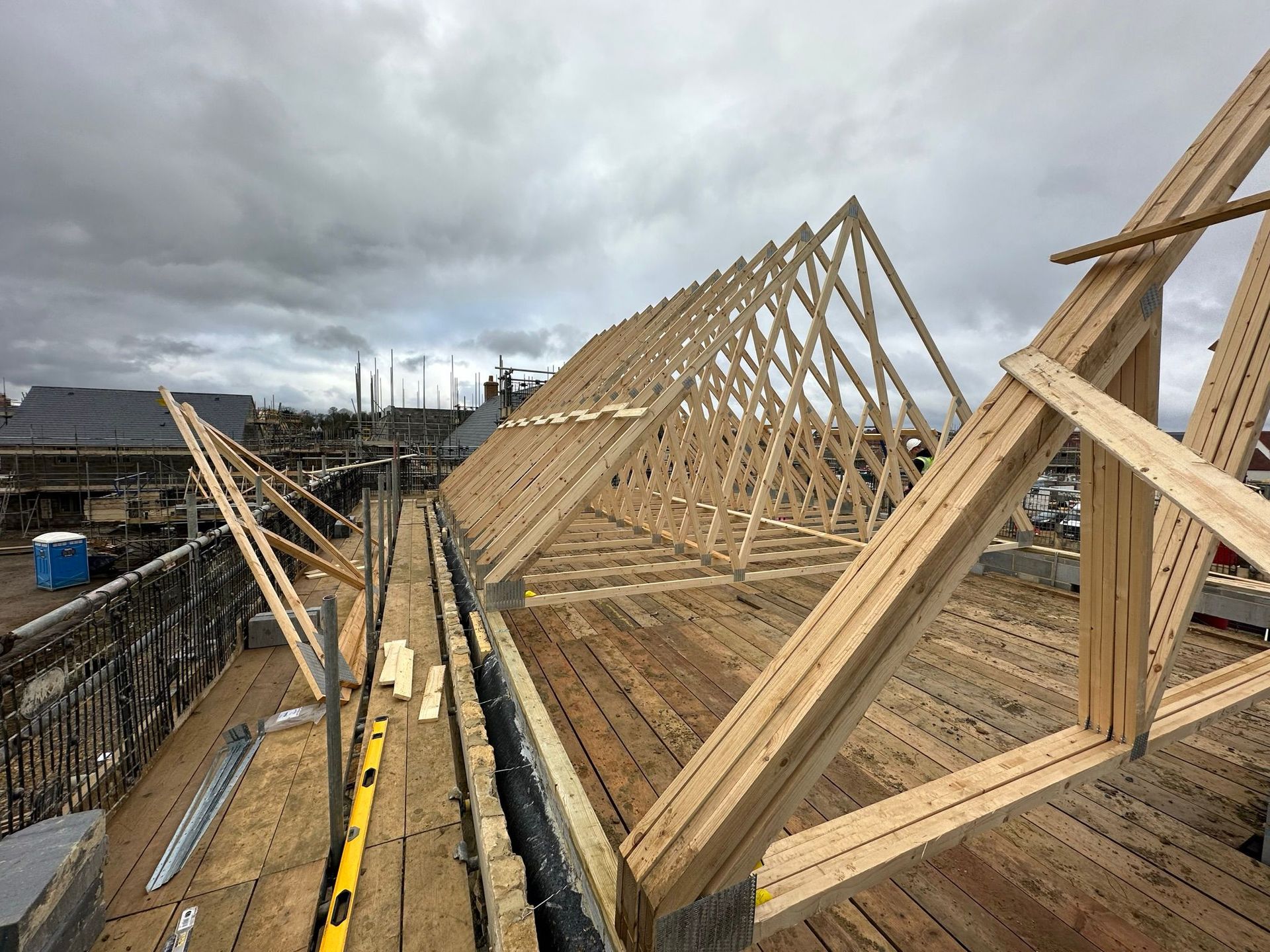 Wooden roof framing construction with a partially built dormer on a brick building.