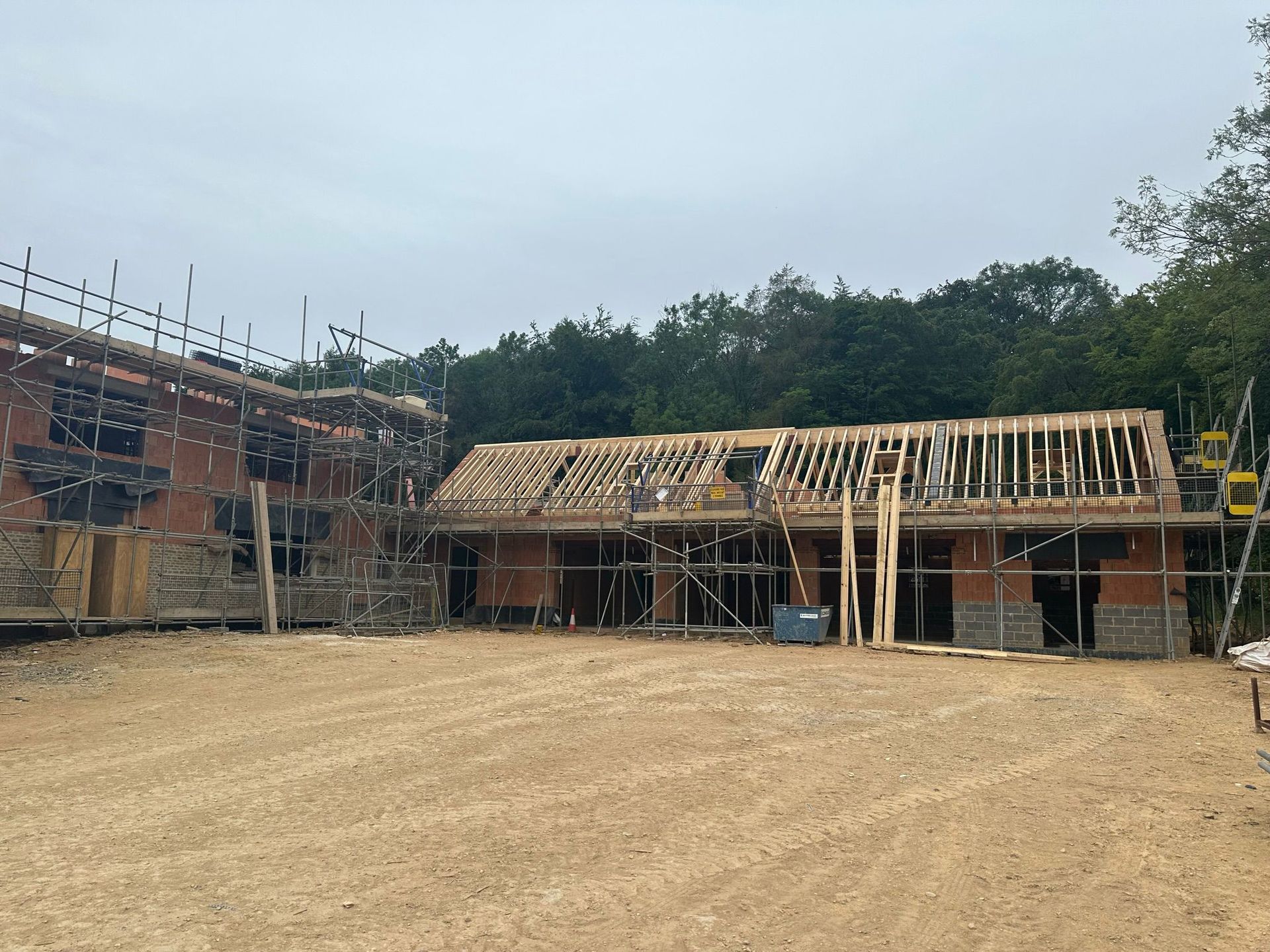 Building under construction with scaffolding, wooden framing, and brick walls.