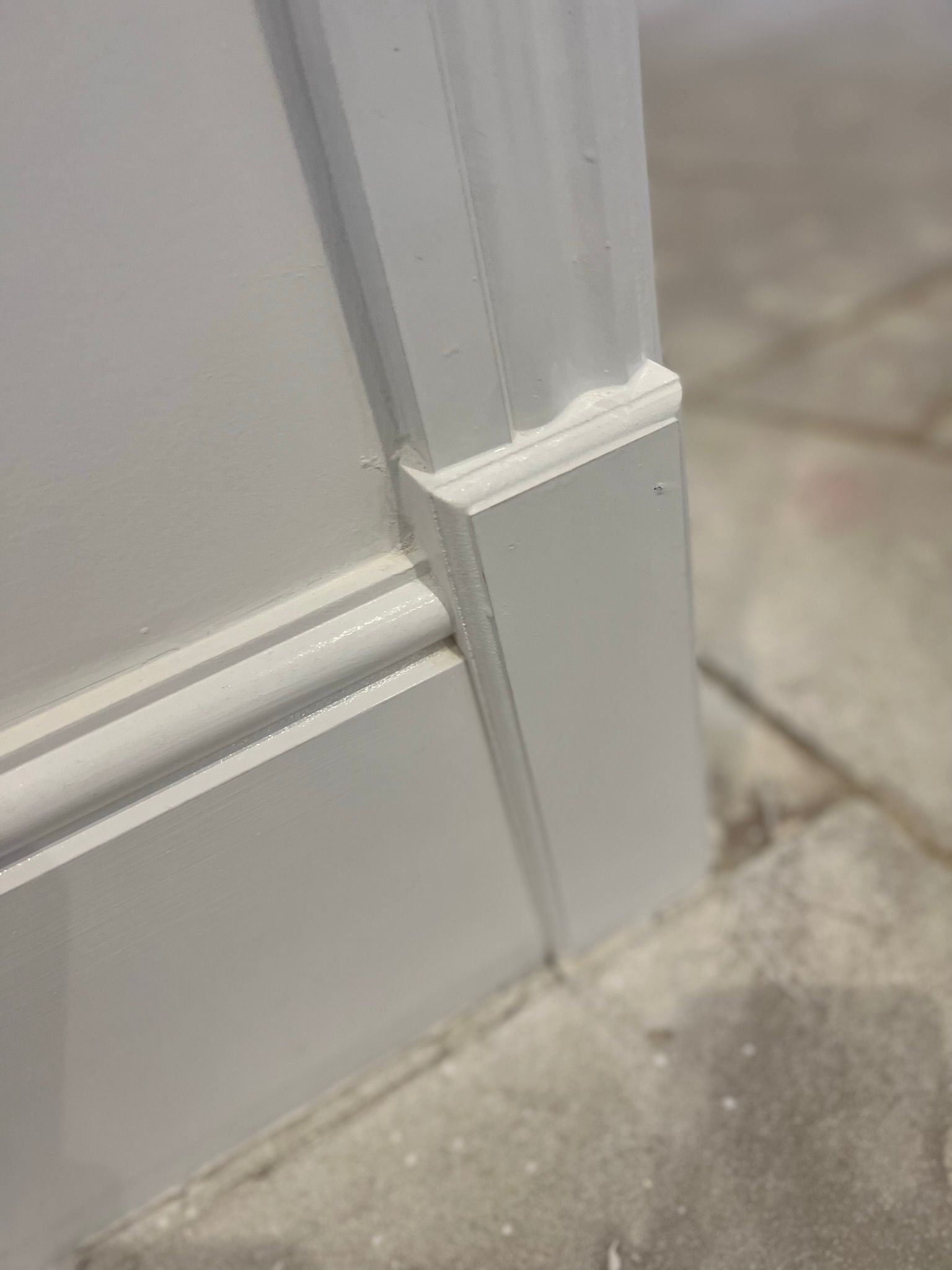 White painted door trim with decorative customized wood on a gray floor.