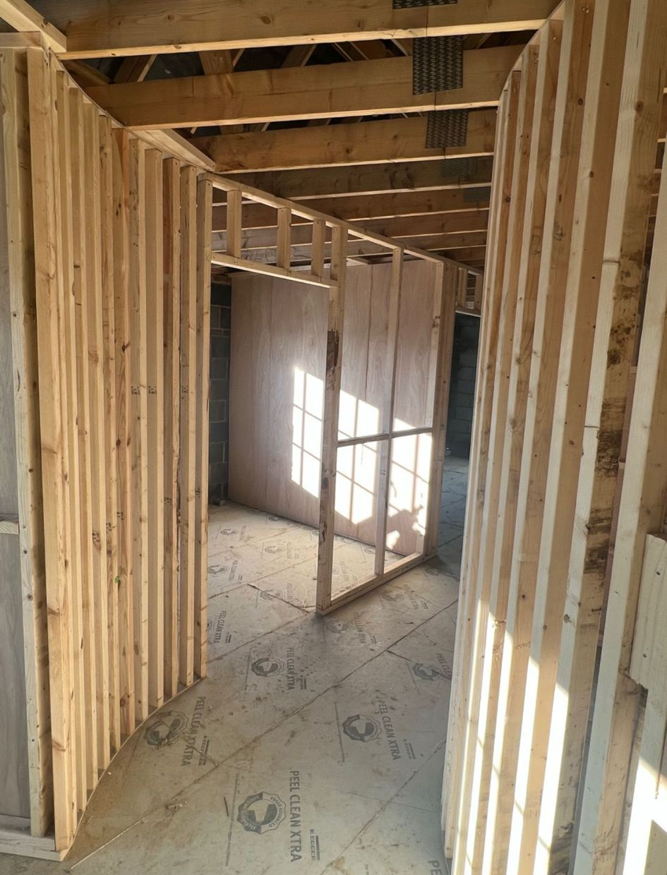 Building under construction with scaffolding, wooden framing, and brick walls.