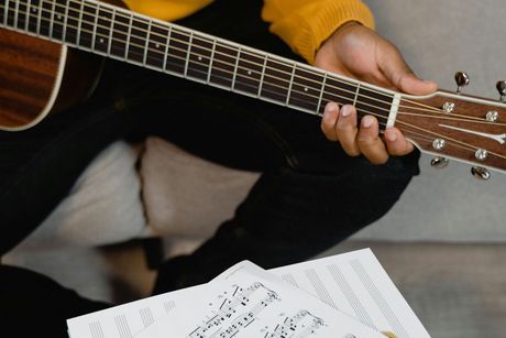 A person in a yellow sweater is playing an acoustic guitar.