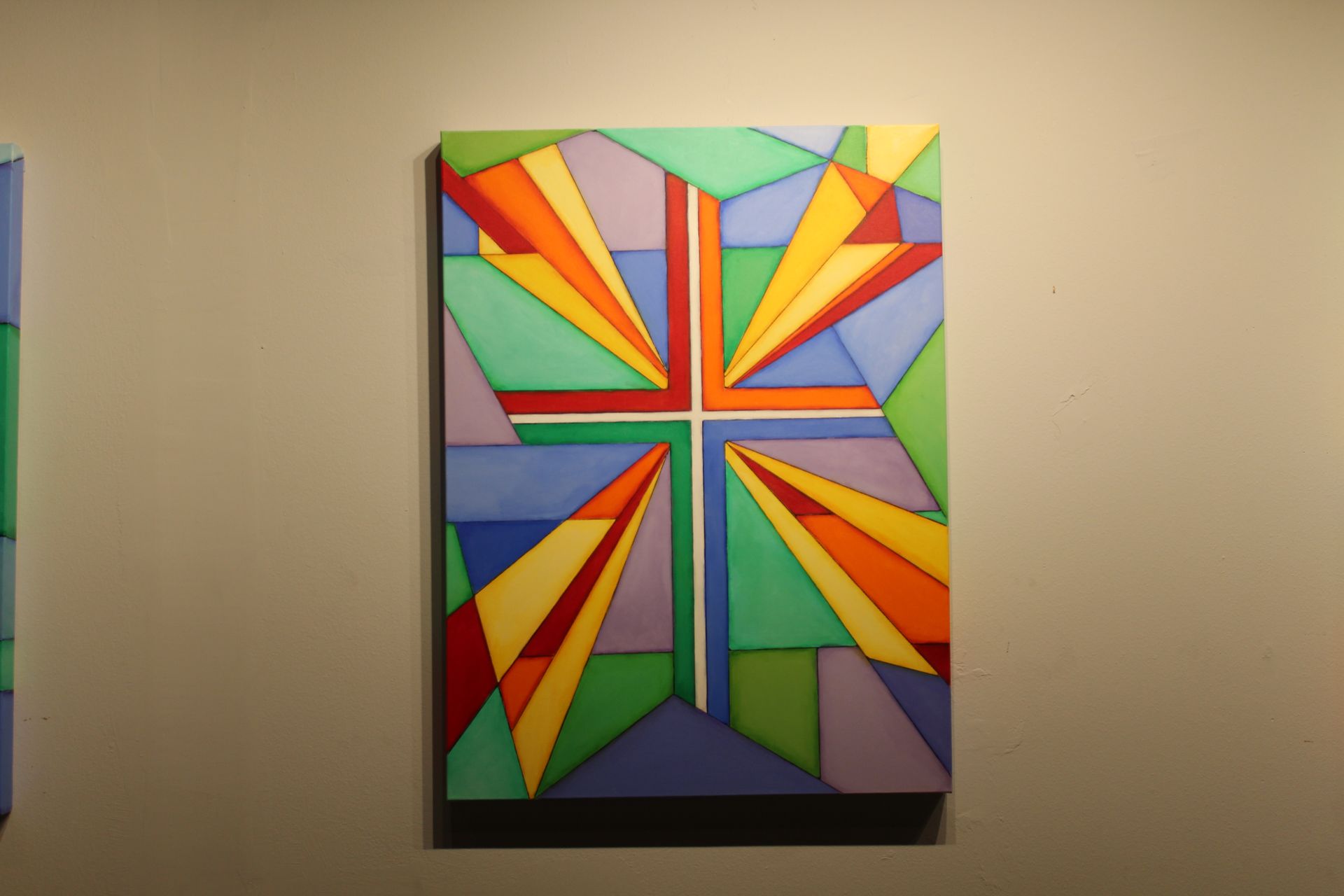 Geometric stained-glass style painting with a cross in the center, featuring a variety of colors like green, blue, yellow, and red.