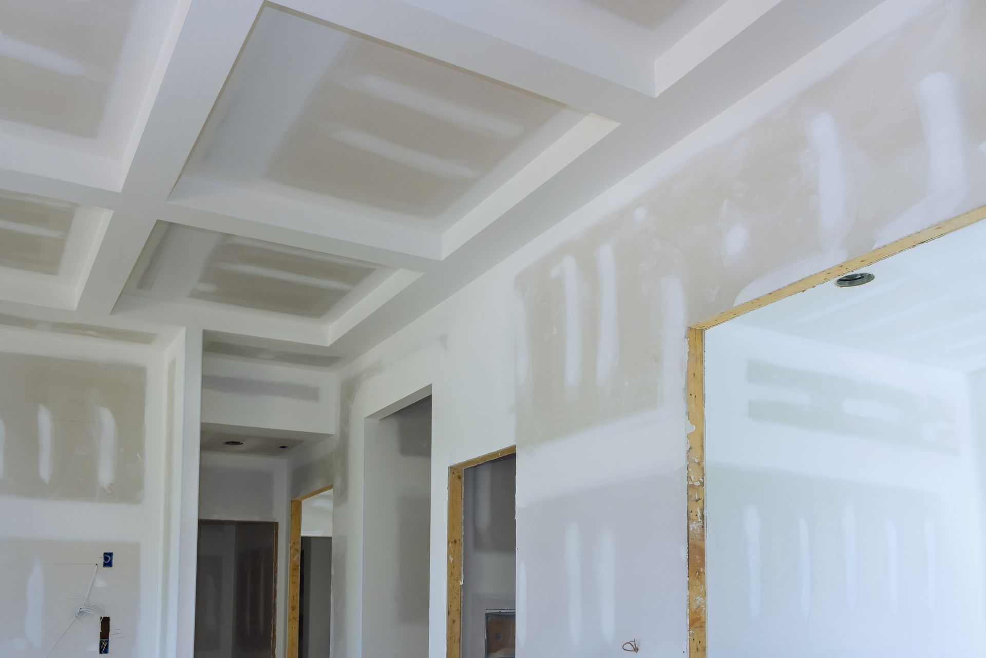 A room with drywall walls and a ceiling in a house under construction.