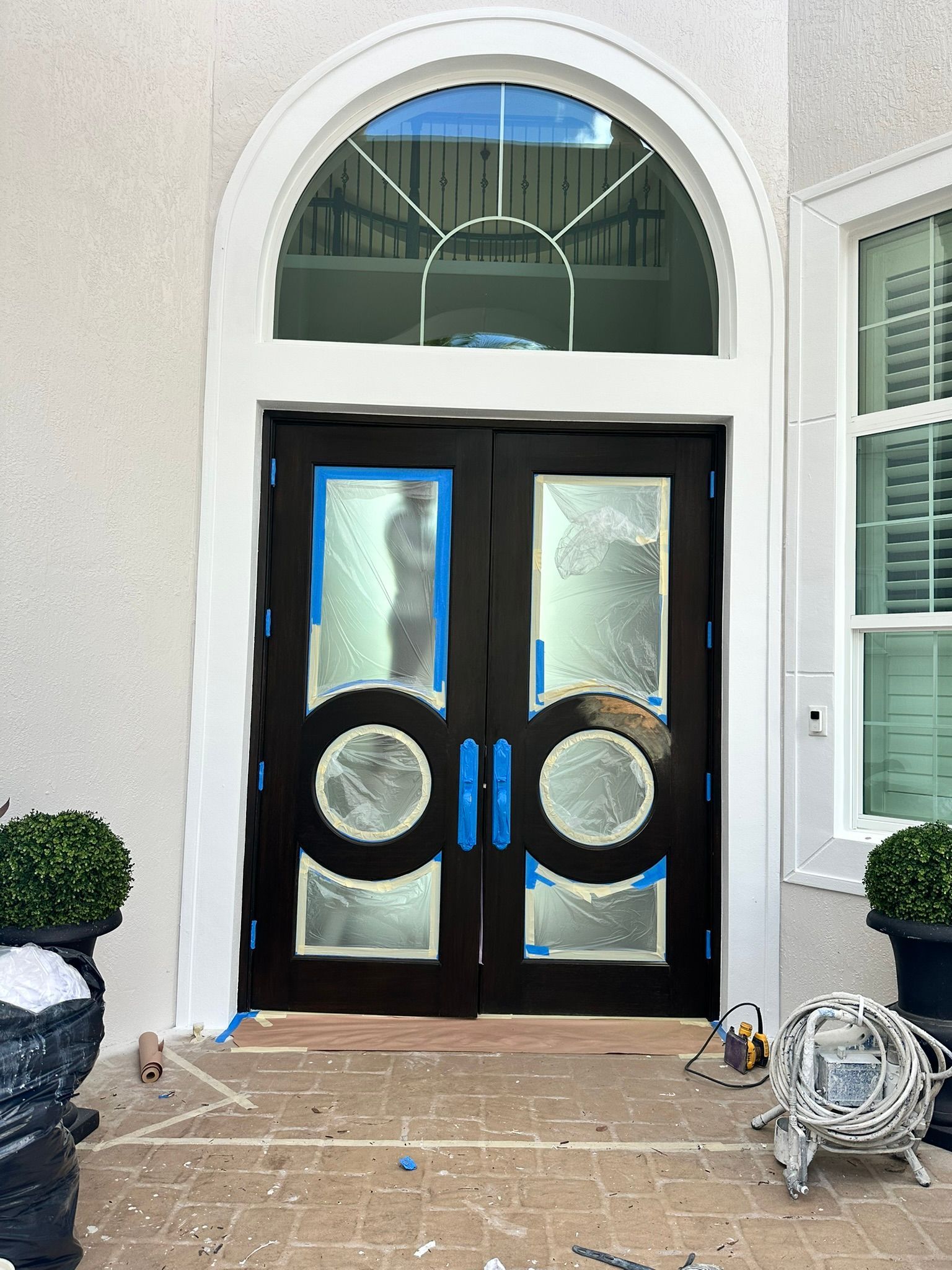 The front door of a house is being painted black.