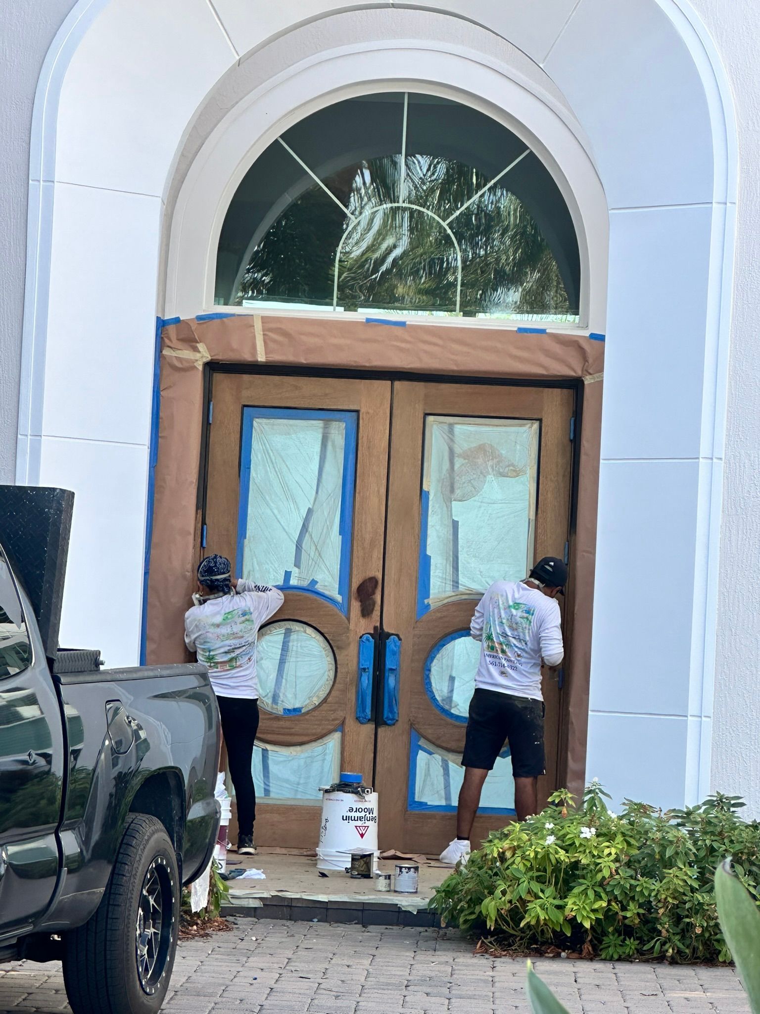 Two men are painting the front door of a house.