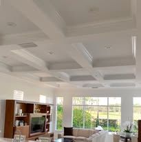 A man is painting the ceiling of a hallway in a house.