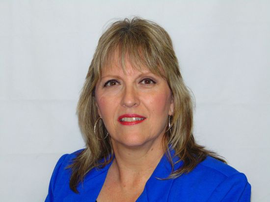 A woman is wearing a blue jacket and smiling for the camera.