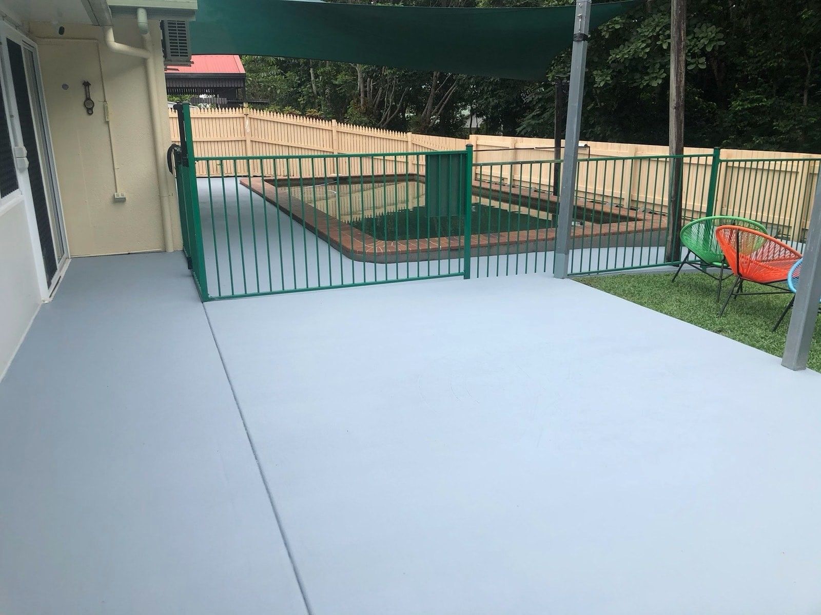 A Man Is Sitting On The Floor Painting A Wall With A Paint Roller — Pete's Painting Solutions In Kewarra Beach, QLD