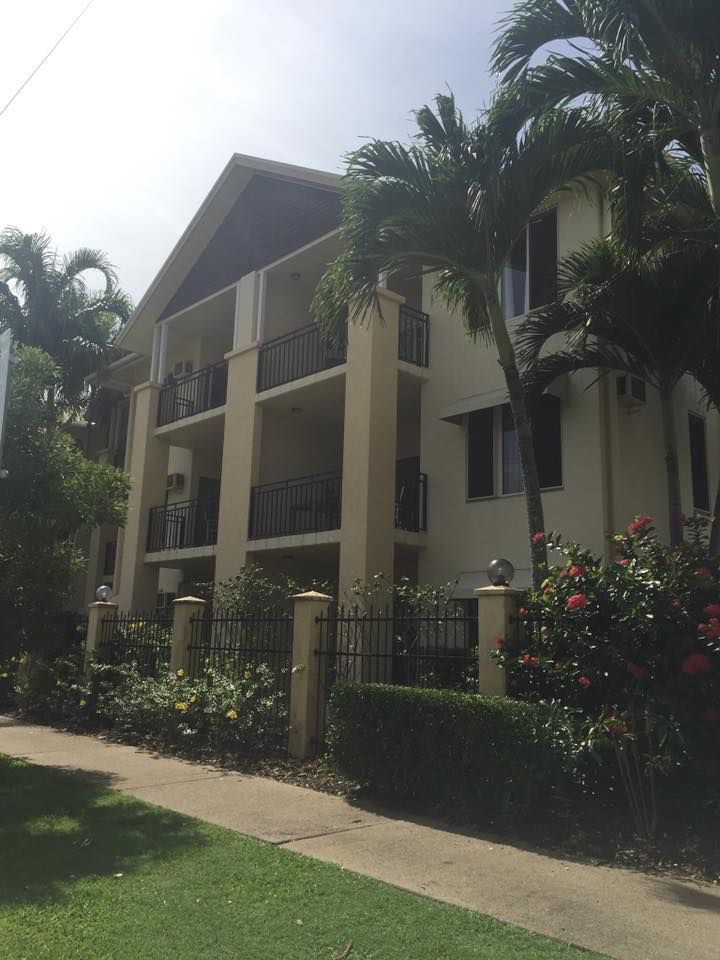 A large building with a fence and palm trees in front of it — Pete's Painting Solutions In Cairns North, QLD