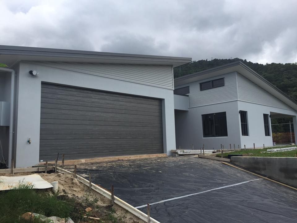 A Man Is Kneeling Down While Painting A Wall With A Paint Roller — Pete's Painting Solutions In Brinsmead, QLD