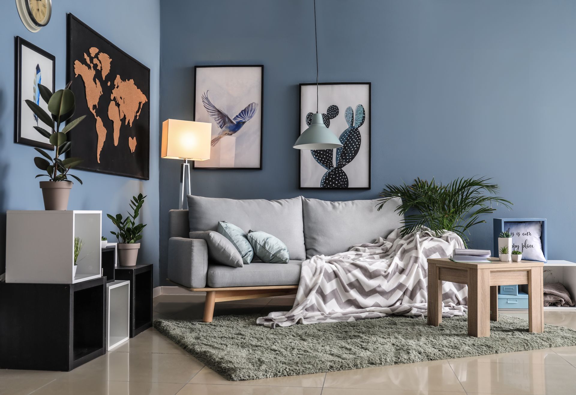 Living room with blue walls, gray couch, rug, and art.
