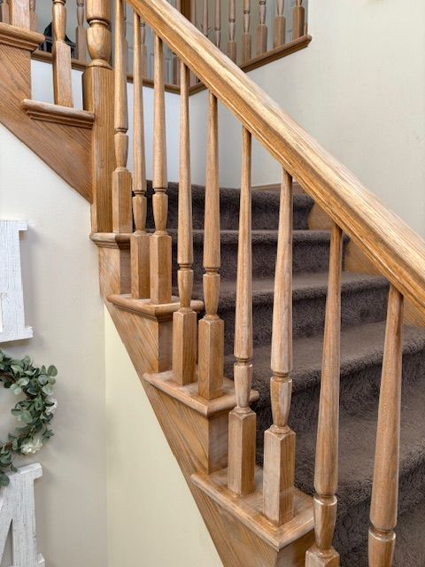 Wooden staircase with brown carpet and light-colored handrails and spindles, against a light-yellow wall.