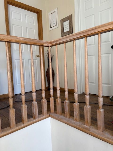 Wooden staircase railing in a home with white walls and doors.