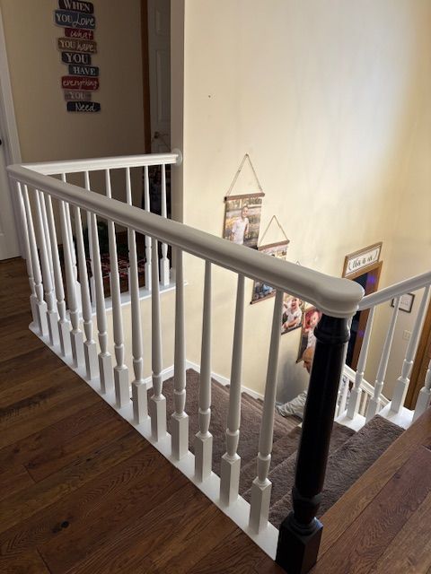 Staircase with white balusters and a dark newel post, leading downward.