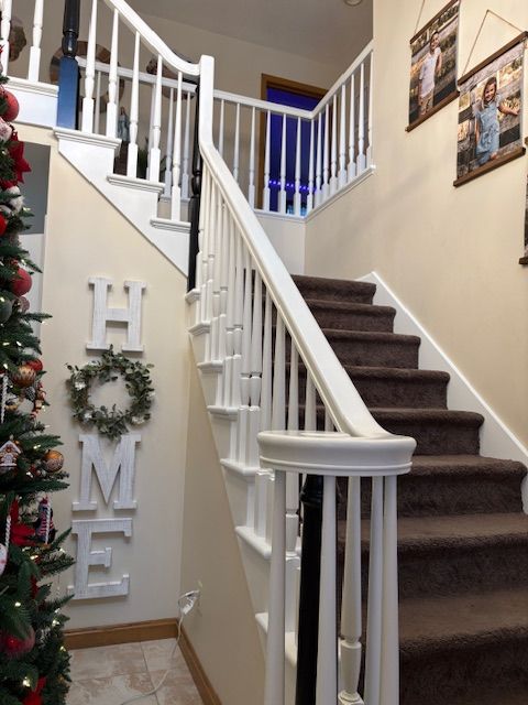A staircase with white banisters and brown carpet. 