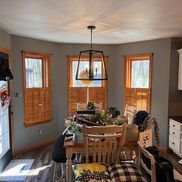 Dining room with table, chairs, windows with shutters, and a hanging light fixture.
