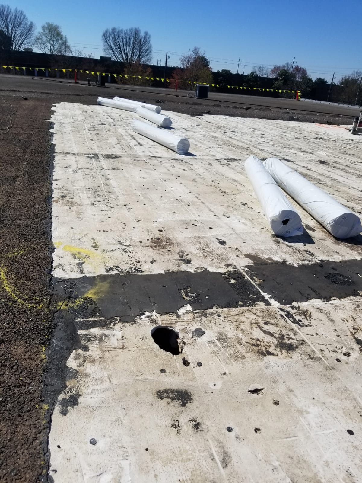 Roof with rolls of white material, part of the roof's surface is removed.