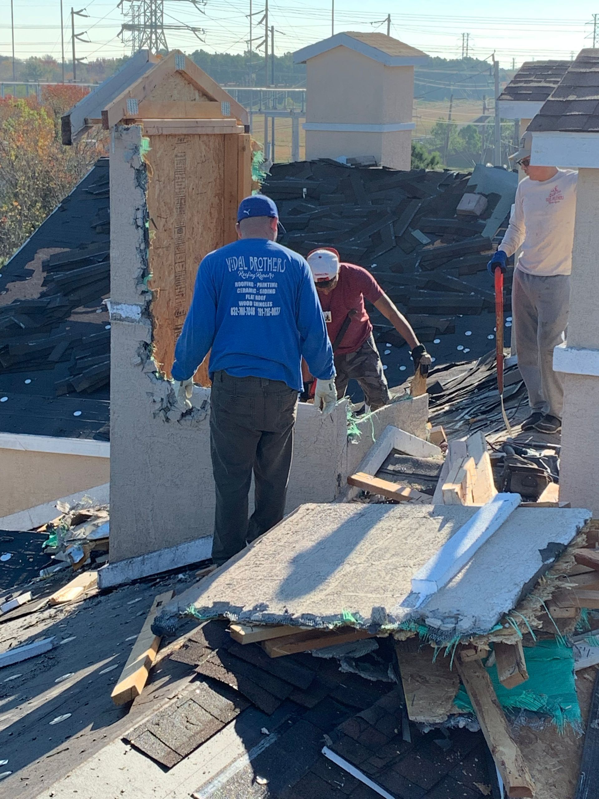Construction workers dismantling a chimney on a rooftop.