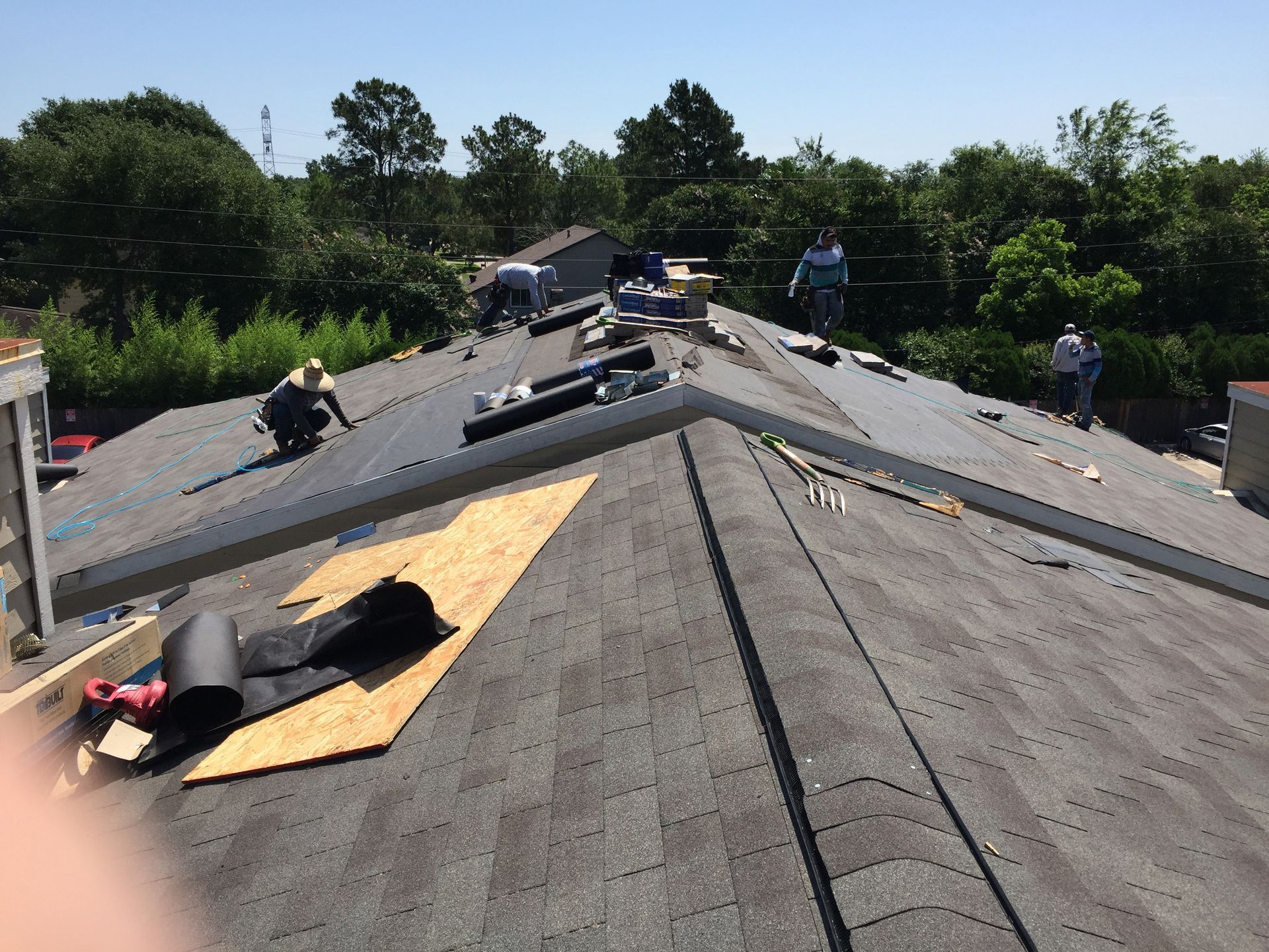Roofers working on a residential roof on a sunny day.