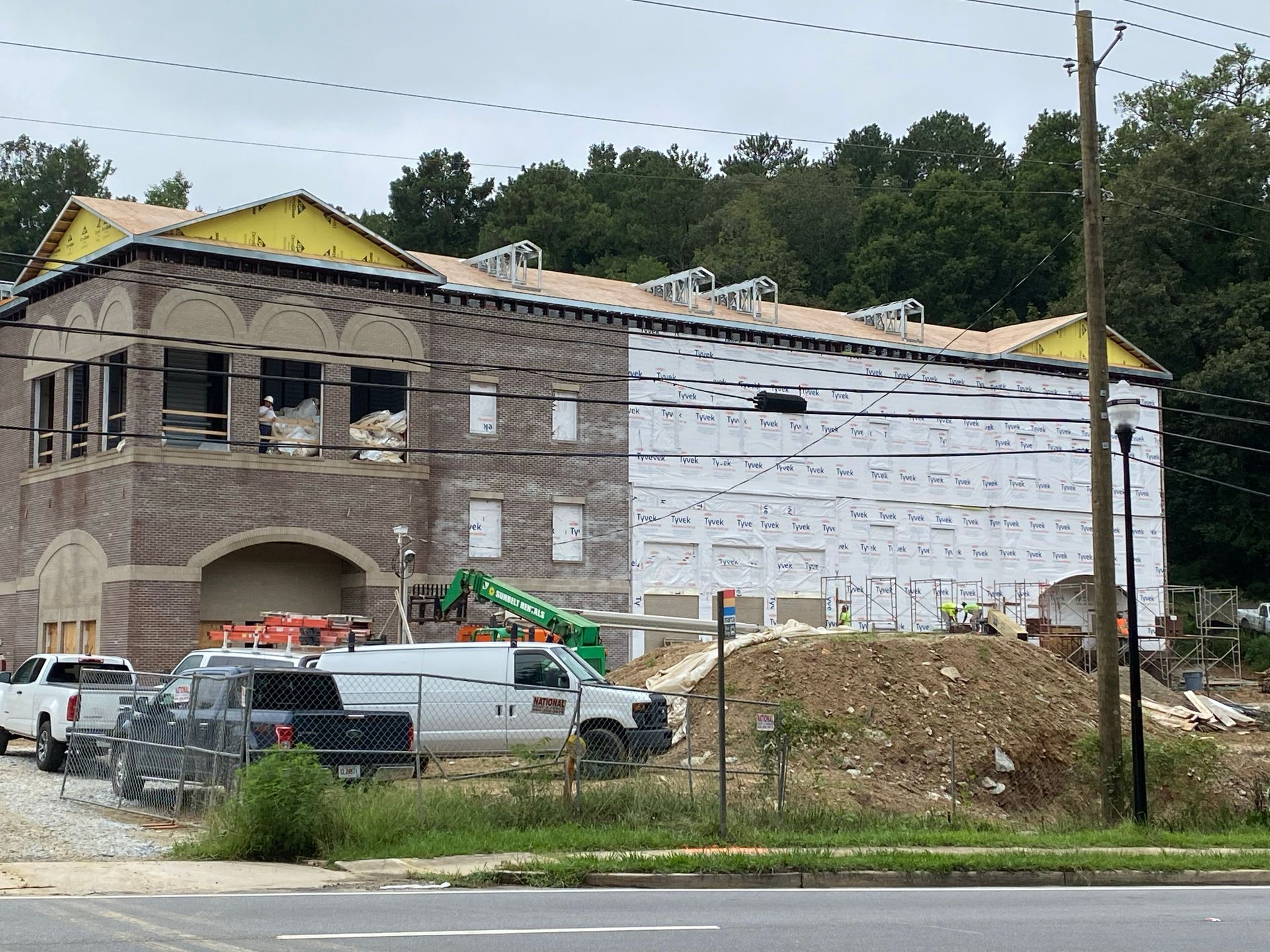Construction site with a partially-built brick building, a white van, and a pile of dirt.