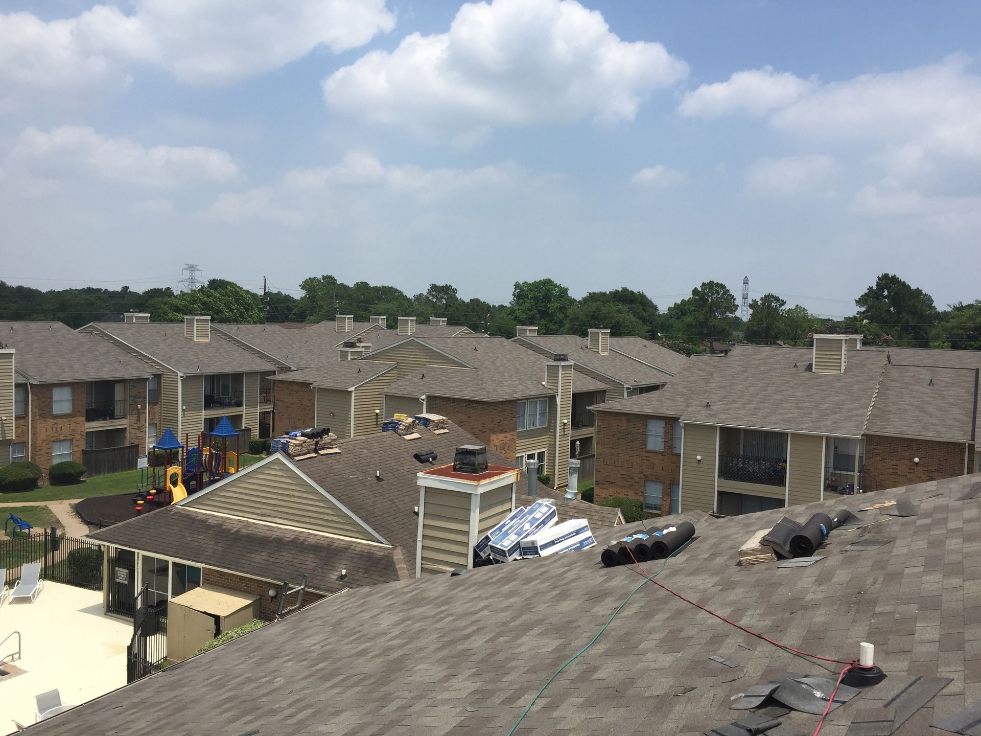 Apartment complex with multiple buildings, some under construction; blue sky with clouds.