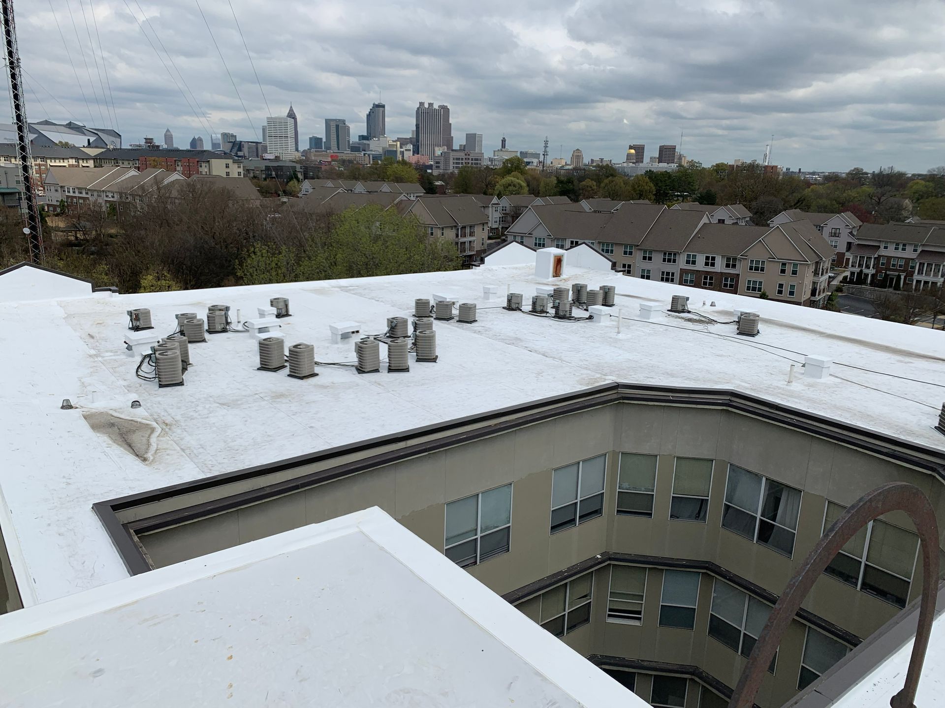 Rooftop view of a building with HVAC units, overlooking a city skyline under a cloudy sky.