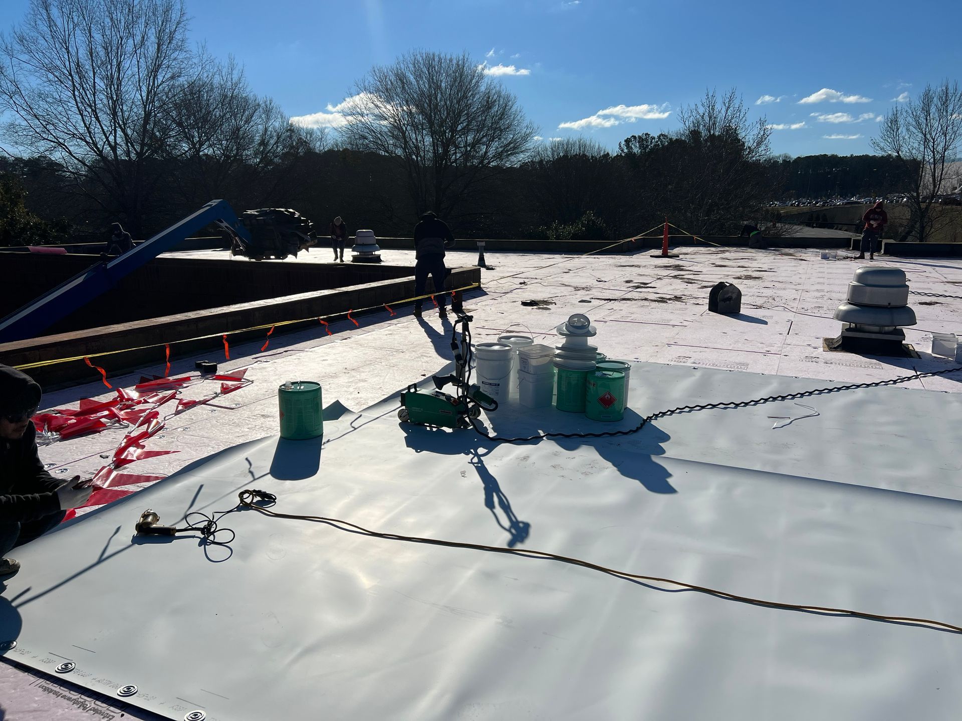 Roof construction site with white membrane, tools, and materials.