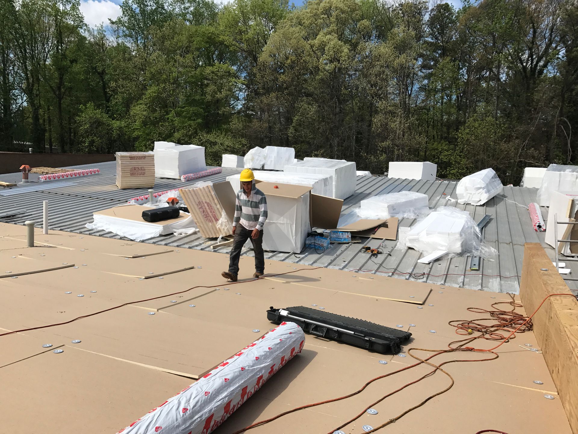Construction worker on a rooftop with insulation and building materials.