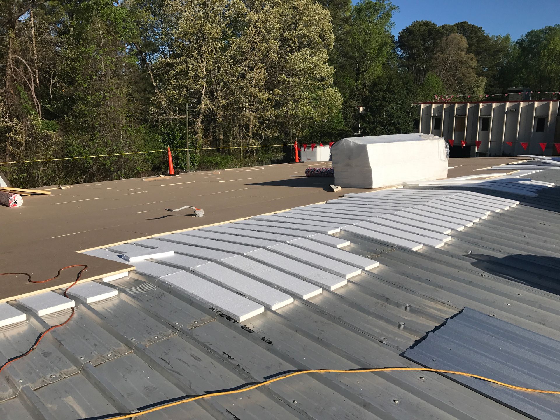 Metal roof with insulation panels being installed; construction site.