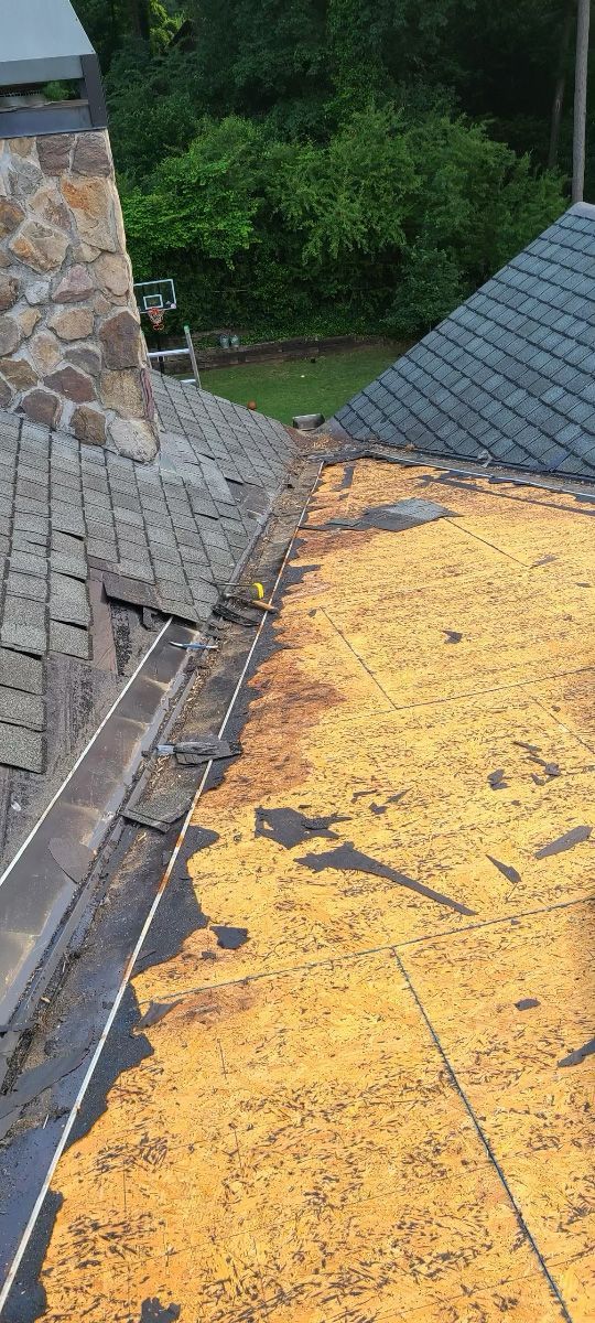 Overhead view of a roof in disrepair, revealing underlayment and debris along the valley.