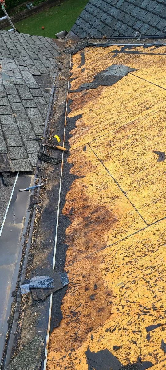 Roof showing old shingles, exposed underlayment, and gutter.