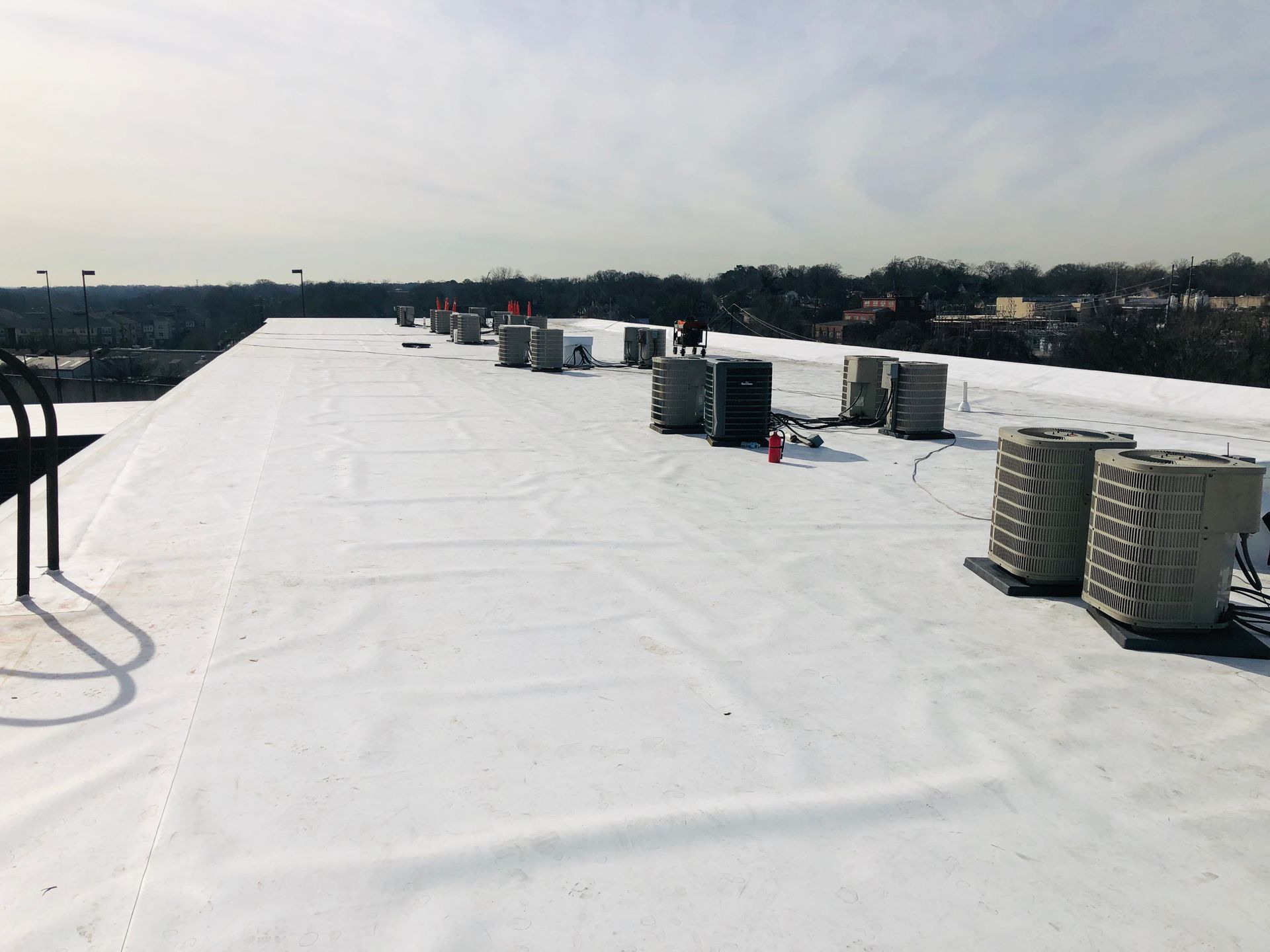 White flat commercial roof with multiple rooftop units on a cloudy day.
