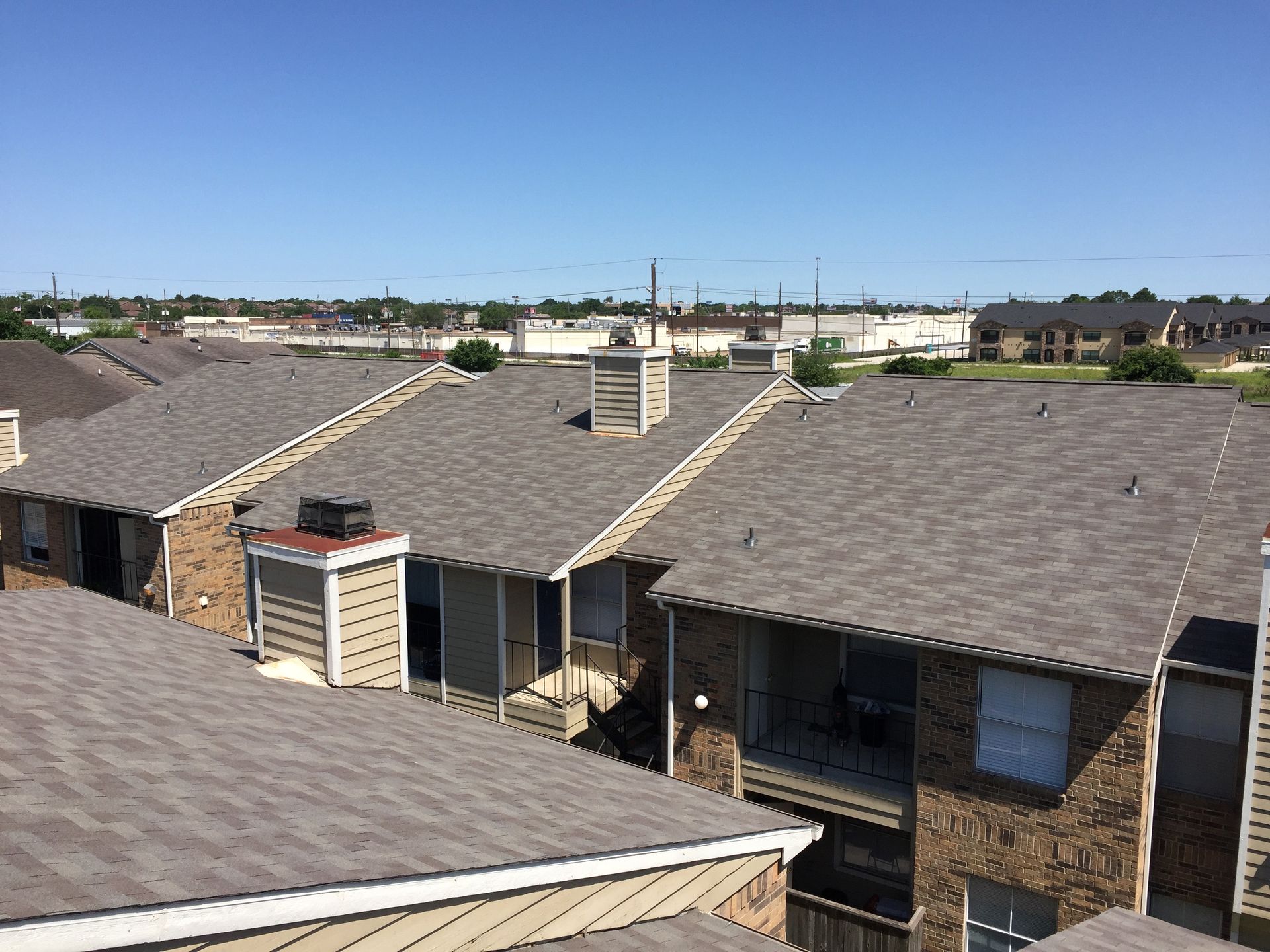 Roofs of a brick apartment complex with chimneys on a sunny day.